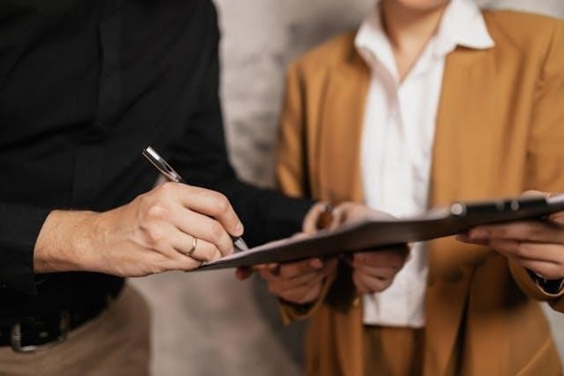 two people looking at a clipboard while one person signs